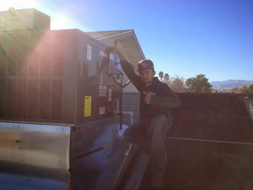 HVAC technician performing Heat Pump Repair on a rooftop unit in Raton